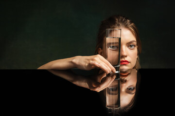 Contemporary art portrait of pretty girl looking through glass of water. Object distortion, optical...