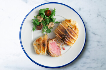 Wellington steak prepared with pork and salad on the side.
