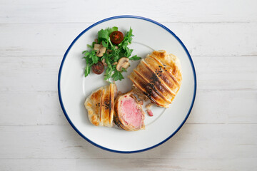 Wellington steak prepared with pork and salad on the side.