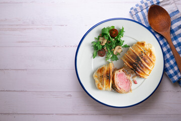 Wellington steak prepared with pork and salad on the side.