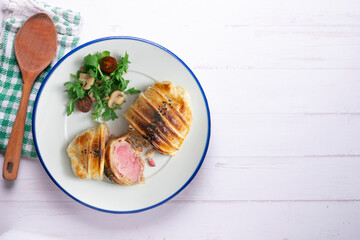 Wellington steak prepared with pork and salad on the side.