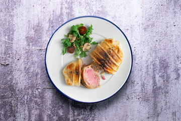 Wellington steak prepared with pork and salad on the side.