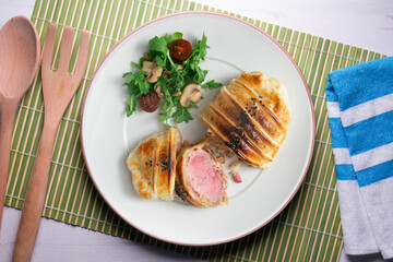 Wellington steak prepared with pork and salad on the side.