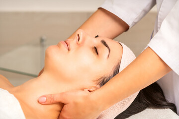 Fototapeta na wymiar Facial massage. Young caucasian woman getting a massage on her neck in a beauty clinic