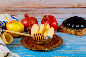Holiday symbols of the Jewish New Year with a shofar, honey jar, fresh apples pomegranates on Rosh...