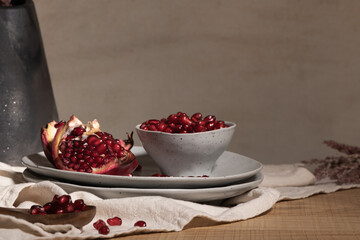 Delicious ripe pomegranate kernels in ceramic bowl on kitchen countertop. Space for text