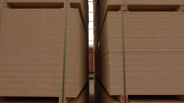 mdf boards and chipboards storing at factory, production, manufacture and woodworking industry concept - chipboards processing. the camera between the rows of chipboard goes back