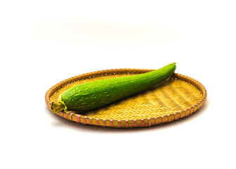 Organic homegrown luffa fruit on handmade flat winnowing basket isolated on white background