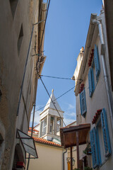 Narrow street with typical mediterranean buildings, church and blue sky (vertical)