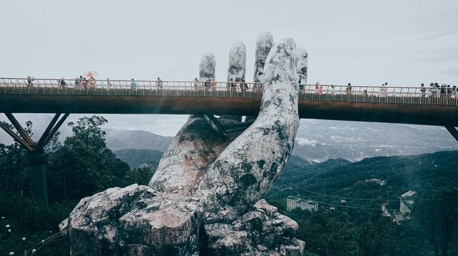 Danang, Vietnam - August 2022: The Golden Bridge is lifted by two giant hands in the tourist resort on Ba Na Hill in Danang, Vietnam. Ba Na Hill mountain resort is a favorite destination for tourists