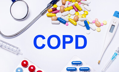 On a white background pills, stethoscope, syringe, thermometer and text COPD Chronic Obstructive Pulmonary Disease. Medical concept