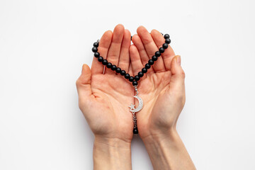 Islamic prayer concept. Hands holding Muslim rosary with silver crescent moon