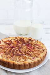 sour cream pie with apples on a white wooden background Milk in a glass