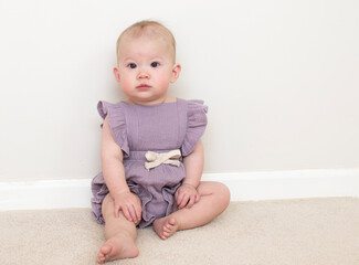 Fototapeta premium Cute caucasian baby girl learning how to sit at 9 month old