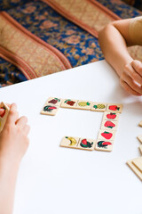 Two children are playing Bingo board Dominoes game. Cozy home. Joy and fun. Play time. Indoor activity. Classes for children of preschool and primary school age. The development of mindfulness.