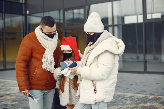 Family standing outdoors wearing face mask and checking passports