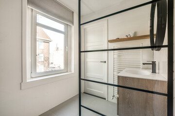 Shower faucets attached to tiled wall near glass partition and ornamental curtail in washroom at...