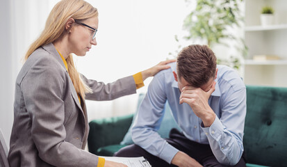 Mature blond woman psychologist helps stressed man, talk about motivation, health care concept