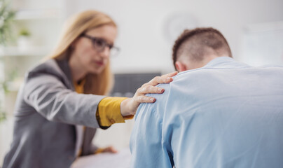 Defocused blond woman psychologist helps stressed patient man sitting in bright doctor office,...