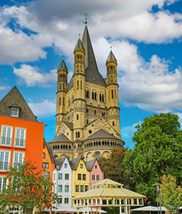 Fototapeta na wymiar Cologne (Buttermarkt), Germany - July 9. 2022: Beautiful market square, colorful medieval old buildings, St. Martin church tower, cafe restaurants, blue summer sky