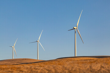 Wind turbines in rural California with dry countryside surrounding