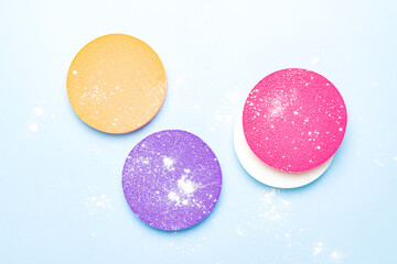 Cosmetic sponges and powdered transparent matte powder on a blue background. The concept of makeup, face cosmetics, skin care. Minimalism, top view.