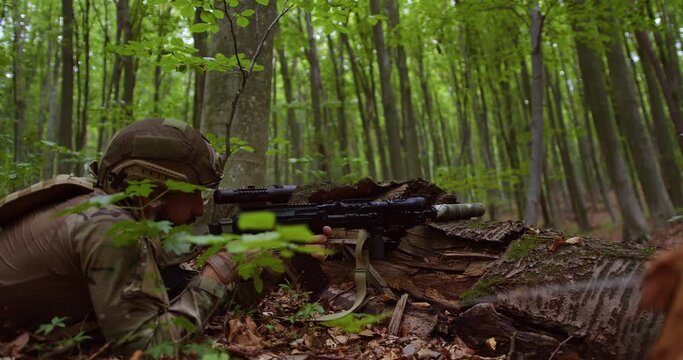 ukrainian sniper lies in the forest and aims and shoots with a rifle from cover. the military fires from a log. close-up