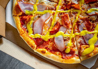 Pizza with Mozzarella cheese, ham, tomato sauce, pepper, pepperoni, sausage and mustard sauce. Italian pizza in box