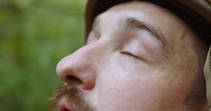 The bearded sweaty tired face of the soldier. The military in the helmet looks into the sky in the helmet. close-up