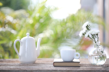 Tea cup and white tea pot with white chrysanthemum in vase
