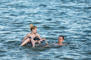 Young guy and girl swim in the lake