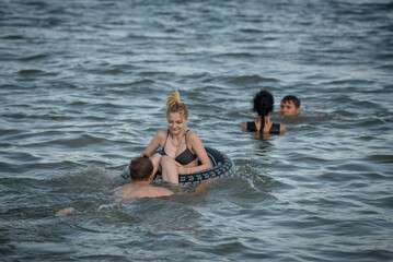 Two young guys and a girl are swimming in the lake