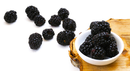 Blackberries in a white plate on a wooden board. Close-up
