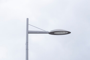a metal-colored street lamp against a gray sky. Street light sources. The infrastructure of a big city and lighting on the streets of the city at night.