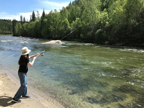 Young Woman Catching Fish. Young Woman Fishing At The River From The Shore