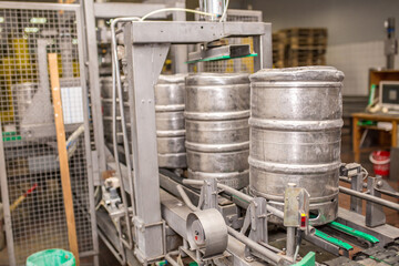 Brewery, bottling beer on aluminum kegs on conveyor lines. Industrial work, automated modern food and beverage production.