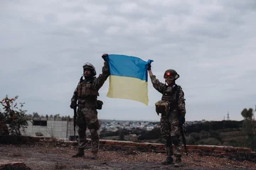 Fotobehang Ukrainian military holds the flag of Ukraine. The concept of victory. The war between Ukraine and Russia. © dsheremeta