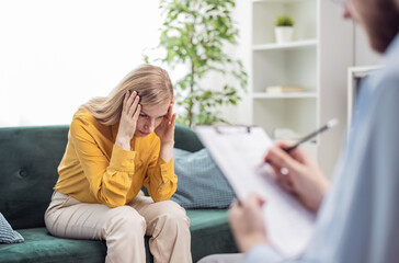 Obraz premium Depressed woman talking about her problems, session of psychology and mental health support, doctor meking notes in bright office