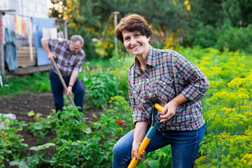woman farmer posing and digging in her estate garden