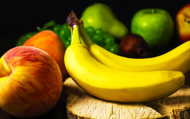 Bananas and peaches on the background of other fruits. Shallow depth of field