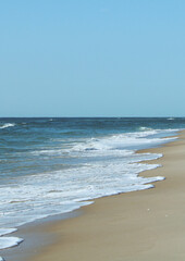 Fototapeta na wymiar waves crashing on the beach with blue sky and blue water