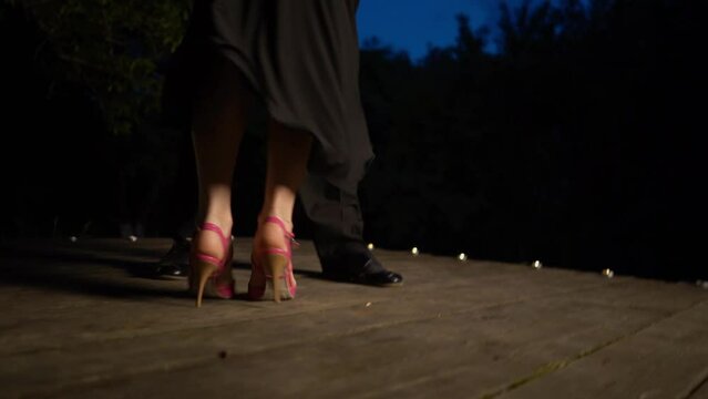 Closeup dancers legs performing latin dance on wooden support. The girl lifts her leg and the camera tilts.