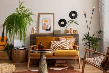 Fotobehang Boho Vintage and cozy space of dining room with mock up poster frame, yellow sofa, wooden coffee table, guitar, plants, commode, decoration and personal accessories. Stylish home decor. Template.   © FollowTheFlow