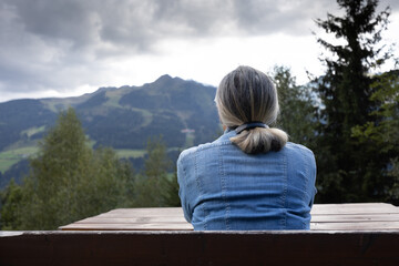 Fototapeta premium A gray-haired woman sits on a bench all alone.