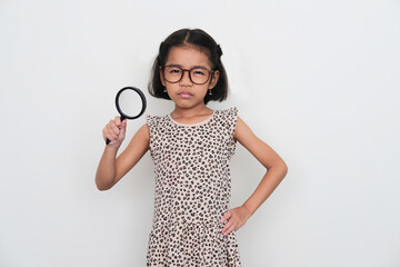 Asian kid looking camera with suspicious expression while holding magnifying glass