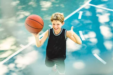 Gardinen portrait of a boy kid playing with a basketball in park © Louis-Photo