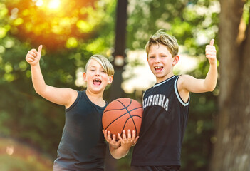 portrait of two boys kids playing with a basketball in park