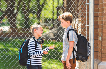Two Elementary school boys outside carrying a backpack