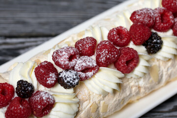 Meringue roll with mascarpone cream. Garnished with raspberries and almond petals. Close-up.