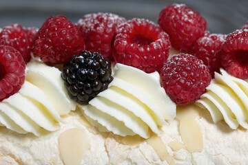 Meringue roll with mascarpone cream. Garnished with raspberries and almond petals. Close-up.